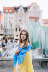 Ukrainian girl with a flag in her hands on the city square.