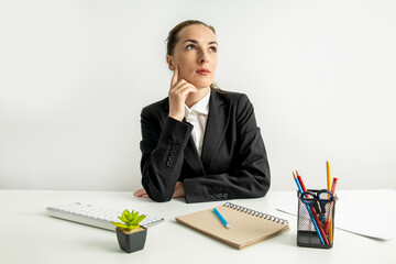 Thoughtful young woman in jacket sitting at table at workplace