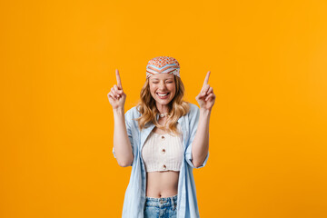 Young blonde woman smiling and pointing fingers upward