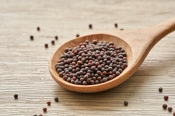 black mustard seed in wood spoon on wooden table background                                                                             