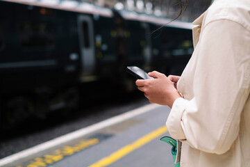 Unrecognizable woman using phone at train station