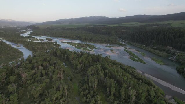 Drone flies over the many arms and streams of the Snake River.  Mountains surround the valley at dusk.