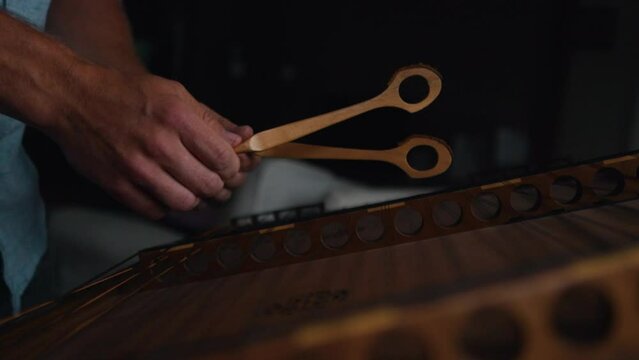 caucasian hands playing hammering dulcimer strings slow motion close up