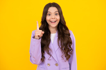 Surprised teenager girl. Funny face of young teenager pointing up with finger, isolated on yellow background. Girl has great new idea.