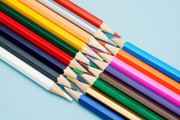水色の上で先が向かい合った綺麗な沢山の色鉛筆