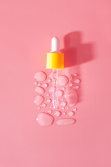 Bottle of drops of anti-aging emulsion and glass pipette on light pink surface close upper view. Skincare and dermatological procedures