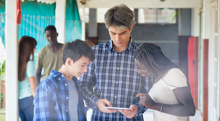 Fototapeta premium Teacher in the school hallway discussing with his teenager multi ethnic classroom