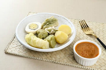 Siomay Bandung (Shumay) or steamed dumplings with boiled egg, tofu, potatoes and cabbage roll. Indonesian traditional street food with peanut sauce and soy sauce, served with green lime.
