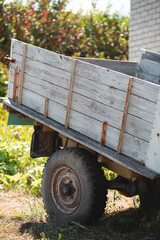 An old abandoned wheelbarrow in the grass near a brick white house against a bright blurry grass on the background