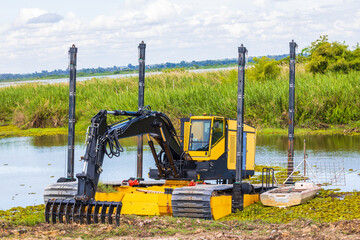 Big powerful excavator digging drainage chanel in swamp in countryside.