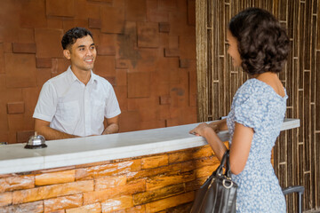 The receptionist smiles welcoming female guests to the hotel lobby
