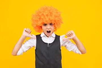 Birthday kids party. Funny kid in curly clown wig isolated on yellow background. Angry teenager girl, upset and unhappy negative emotion.