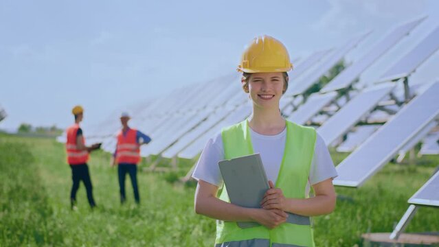 Large smiling ecological engineer woman posing in the middle of photovoltaic solar panels farm concept of green energy and ecological energy
