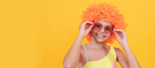 funny kid in curly clown wig. having fun. child wear sunglasses and swimsuit. Funny teenager child on party, poster banner header with copy space.