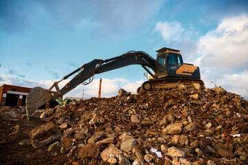 Building excavator on concrete pieces at demolition site