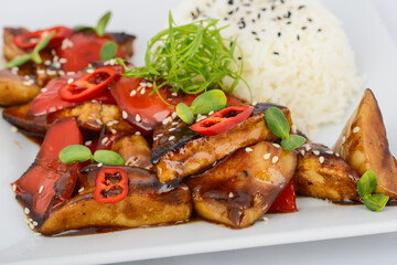 rice with chicken, chili pepper and vegetables on a white plate, macro photo
