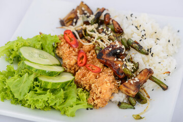 Thai rice with chicken and vegetables in a plate on a white background, macro photo
