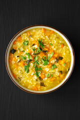 Homemade fresh lemon rice soup in a bowl on a black background, top view. Flat lay, overhead, from above.