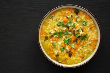 Homemade fresh lemon rice soup in a bowl on a black surface, top view. Flat lay, overhead, from above. Copy space.