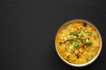 Homemade fresh lemon rice soup in a bowl on a black surface, top view. Flat lay, overhead, from above. Space for text.