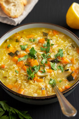 Homemade fresh lemon rice soup in a bowl on a black surface, side view. Close-up.