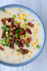 Homemade Corn Chowder with Bacon in a Bowl on a white wooden background, top view. Flat lay, overhead, from above.