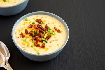 Homemade Corn Chowder with Bacon in a Bowl on a black background, side view. Copy space.