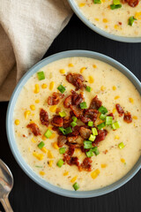 Homemade Corn Chowder with Bacon in a Bowl on a black surface, top view. Flat lay, overhead, from above.