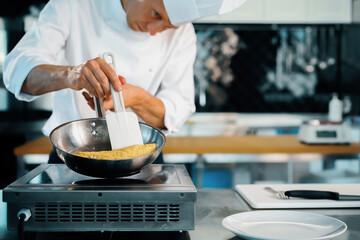 Close-up of a chef preparing a french omelette on a frying pan in a professional kitchen