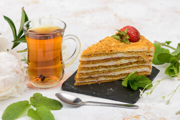 dessert honey cake on black slate on a white background with tea

