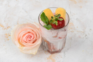 strawberry tiramisu dessert in a glass decorated with strawberries and a mint leaf on a white background with a flower
