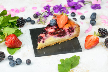 berry cheesecake decorated with strawberries on black slate
