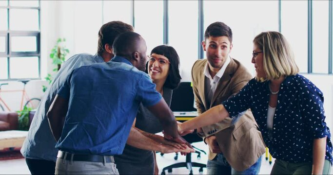 Fun and motivated group or team of creatives joining their hands together in a huddle in their office. Diverse business people celebrating a plan or strategy after brainstorming ideas and success