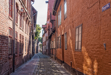 Fototapeta na wymiar A typical alley with slanting houses at the old town of Lüneburg, the Papenstrasse