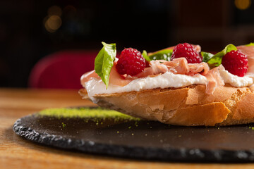 Italian bruschetta with cheese and prosciutto, fresh raspberry