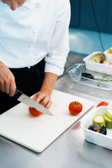 Obraz na płótnie Canvas Close-up of a chef slicing tomato in a professional restaurant kitchen