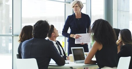 Mature female manager talking in meeting with professional business people. Senior executive businesswoman, pointing at digital presentation on tablet in corporate office, with a team of colleagues. - Powered by Adobe