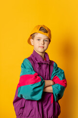Stylish kid boy in 80s sport suit and cap on yellow background - 520974596