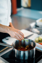 Professional restaurant kitchen, close-up: the chef throws greens into the pan