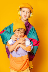 Two kids in stylish vintage 80s clothes have a fun on yellow background