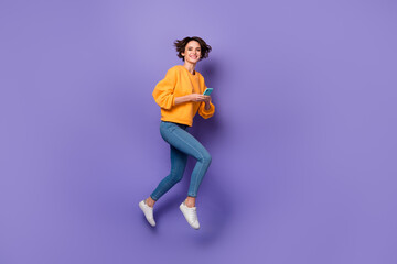 Fototapeta na wymiar Full length body size view of attractive cheerful girl jumping using device blog post isolated over violet lilac color background