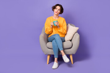 Portrait of attractive girly minded girl sitting drinking latte creating strategy isolated over violet lilac color background