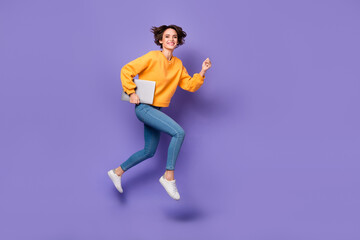 Fototapeta na wymiar Full length body size view of attractive trendy motivated girl jumping running carrying netbook isolated on violet lilac color background