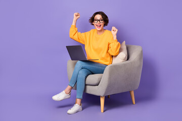 Portrait of attractive cheerful girl sitting using netbook rejoicing breakthrough isolated over...