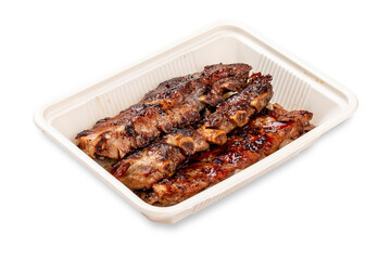 Grilled pork ribs. In a plastic container. Food to go. On a light background.