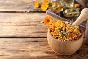 Mortar of dry calendula flowers on wooden table. Space for text - obrazy, fototapety, plakaty