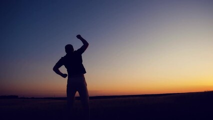 Winner concept: Silhouette of champion man on golden sunset background