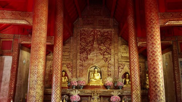 Inside the ancient Wat Phra Singh temple in Chiang Mai in Thailand, camera panning up to the wooden framework structure.