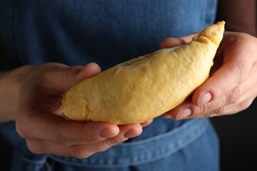 Woman holding piece of durian on dark background, closeup