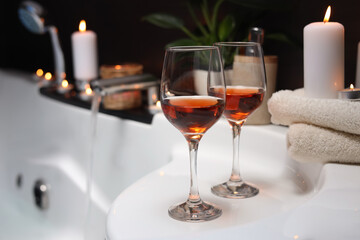 Bathtub with glasses of wine and candles indoors. Romantic atmosphere